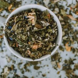 Overhead shot of a cup with a blend of dried herbal tea leaves and flowers.